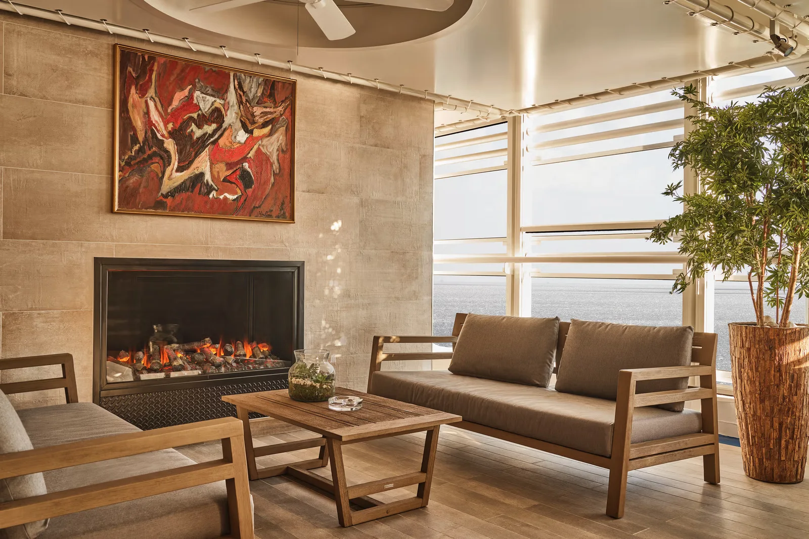Lounge with a lit fireplace and panoramic ocean views aboard a Silversea ship
